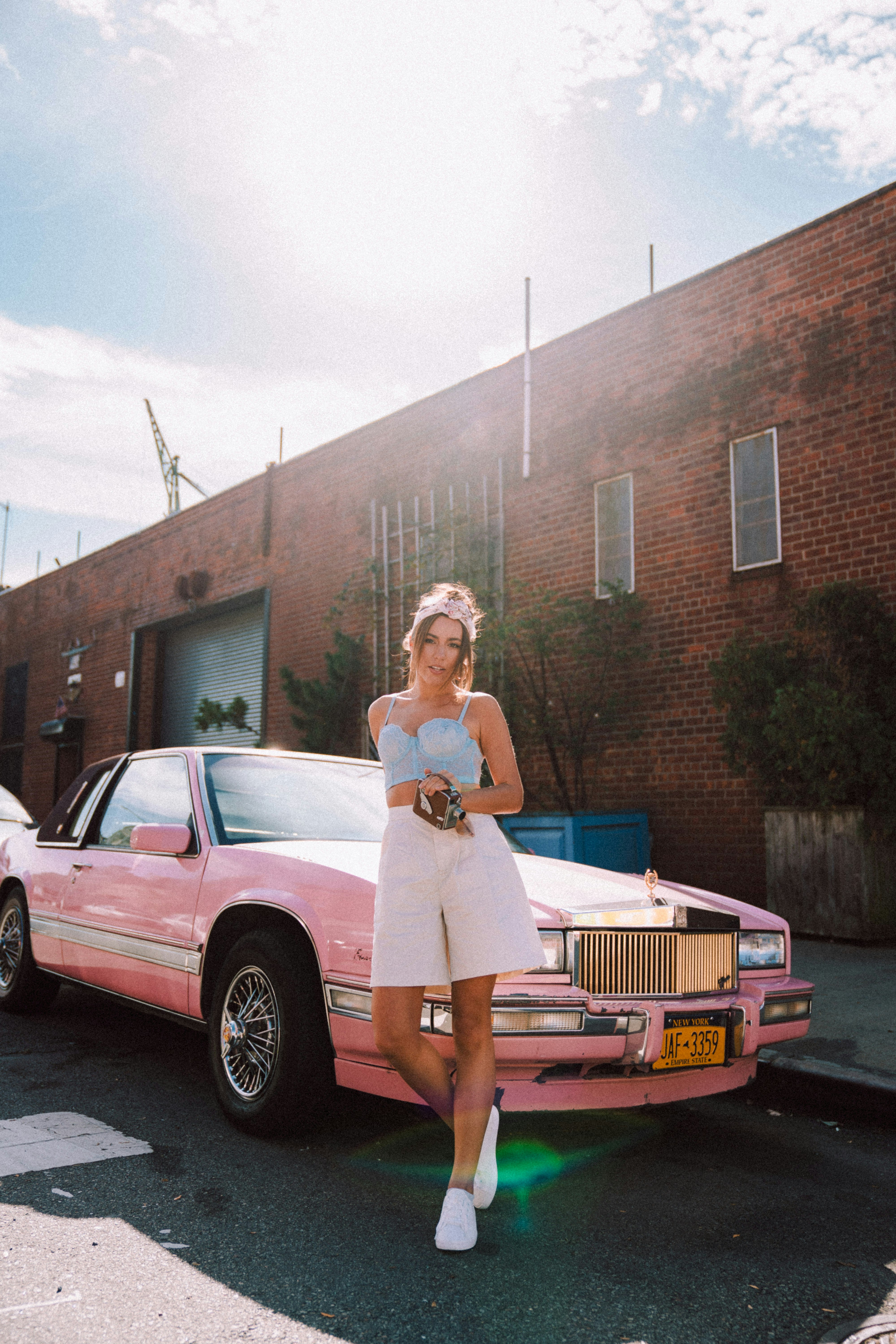 woman in white dress standing beside pink sedan during daytime